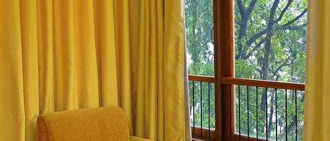 A room with a large window, yellow curtains, and a yellow armchair.
