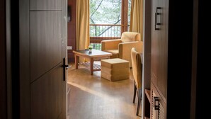 A room with a wooden floor, a sofa, a table, and a window with curtains. - The Golden Crest (Gangtok)