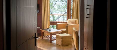A room with a wooden floor, a sofa, a table, and a window with curtains.