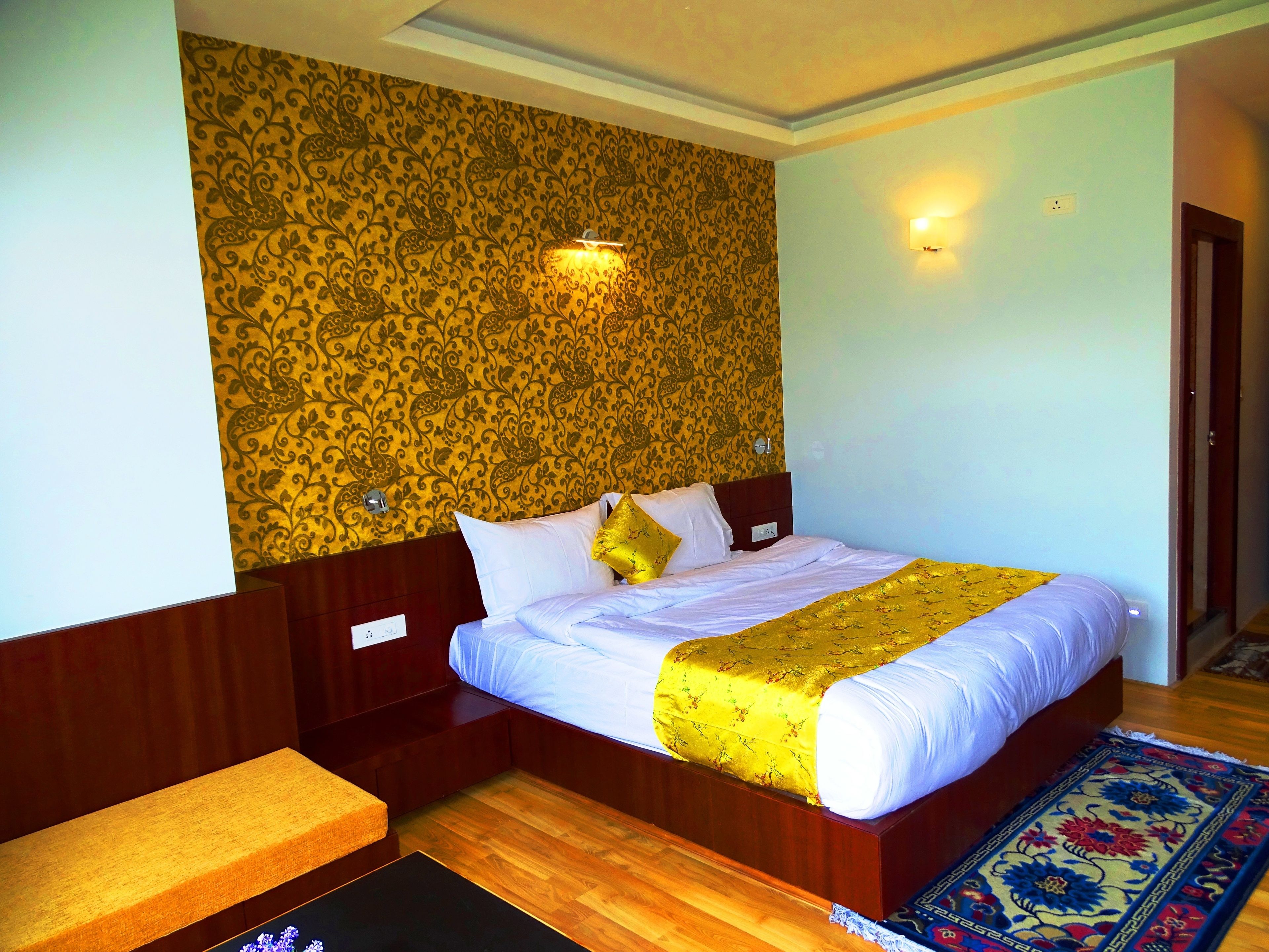 Ein Hotelzimmer mit Bett, Nachttisch und einer Wand mit Muster.