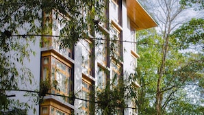 A multi-story building with large windows and balconies, surrounded by lush greenery. - The Golden Crest (Gangtok)