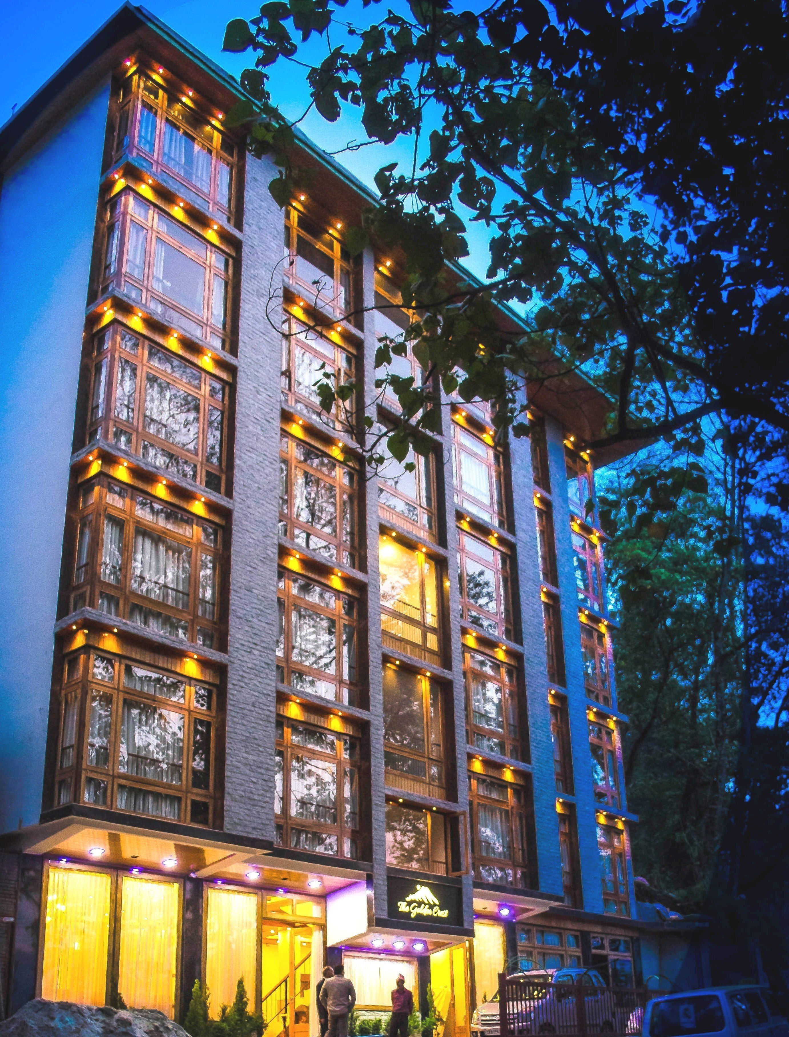 A multi-story building with large windows, a sign reading "The Golden Crest," and a visible entrance area with steps and a railing.