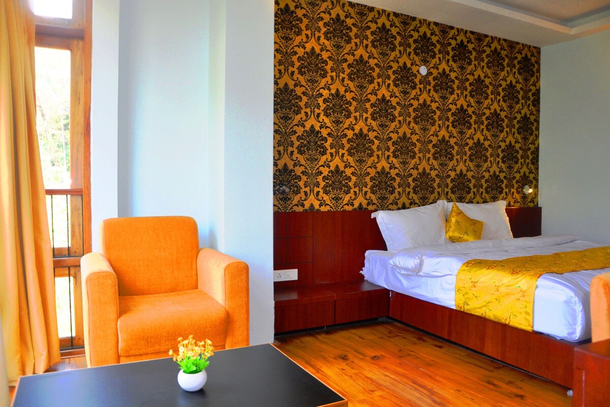 Une chambre d’hôtel avec un lit, un canapé, une table et une fenêtre avec des rideaux.