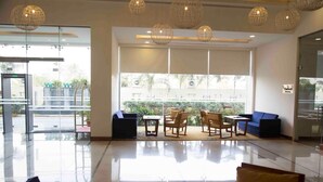 A spacious lobby with a glass wall, a seating area with chairs and a sofa, and a reception desk.