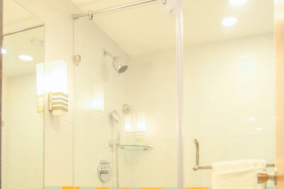 A bathroom with a glass shower enclosure, a sink, and a towel rack.
