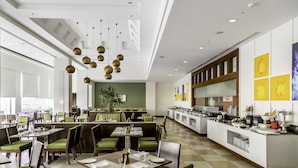 A modern restaurant with green upholstered booths, a central dining area, and a buffet counter.