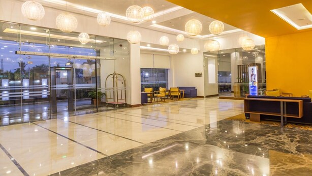 A modern lobby with glass doors, seating areas, and decorative spherical lights.