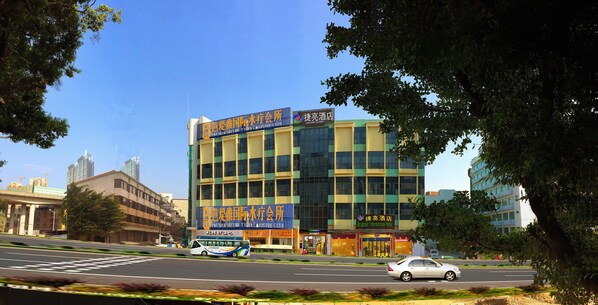 A modern building with a large sign for a hotel and a bus in front. - Cheng Yue Selected Hotel Guangzhou Junye Nangang Branch (Guangzhou)