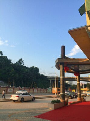 A parking area with a white car, a bus, and a pedestrian. - Cheng Yue Selected Hotel Guangzhou Junye Nangang Branch (Guangzhou)