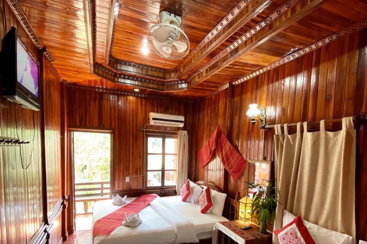 Une pièce en bois avec deux lits, un ventilateur de plafond et un téléviseur.