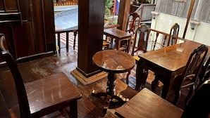 A wooden interior with tables and chairs, a wooden ceiling, and a view of the outside. - Soutikone 1 Guesthouse (Luang Prabang)