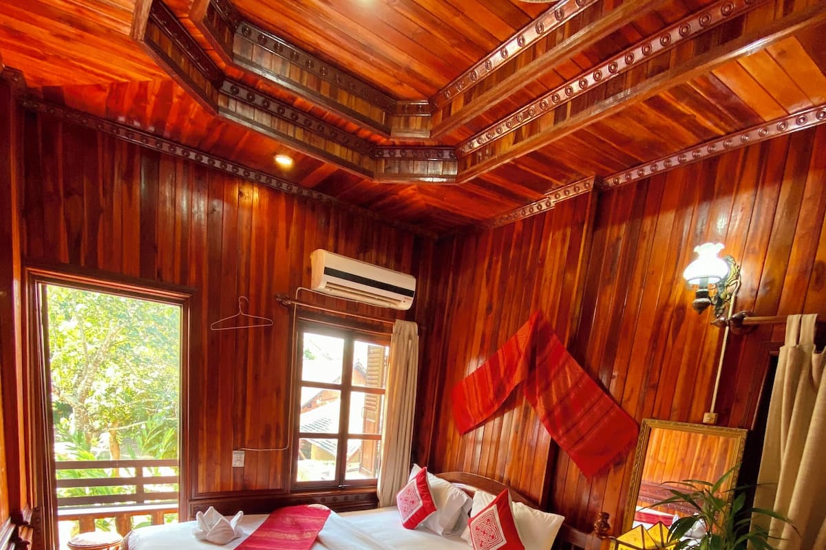 Une pièce en bois avec deux lits, une table avec une lampe et une fenêtre.