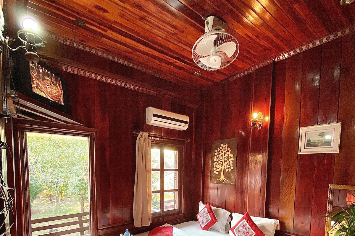 Une pièce en bois avec un lit, un appareil de climatisation, une fenêtre et un ventilateur de plafond.
