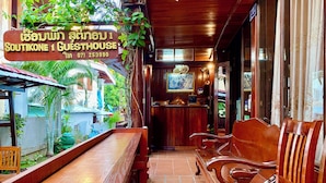 A guesthouse interior with wooden furniture, a reception desk, and a signboard. - Soutikone 1 Guesthouse (Luang Prabang)