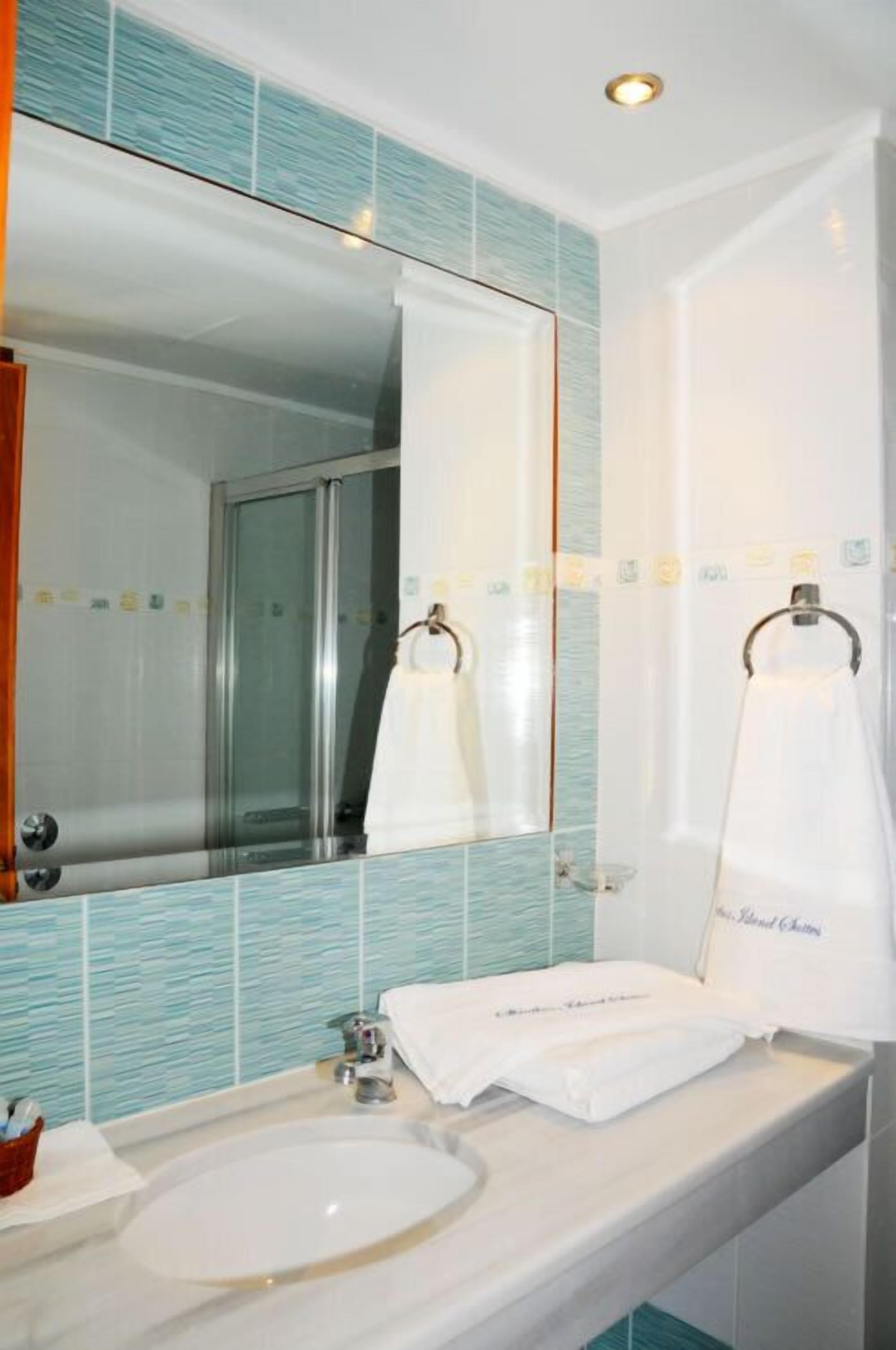 A bathroom with a large mirror, a sink, and a shower.