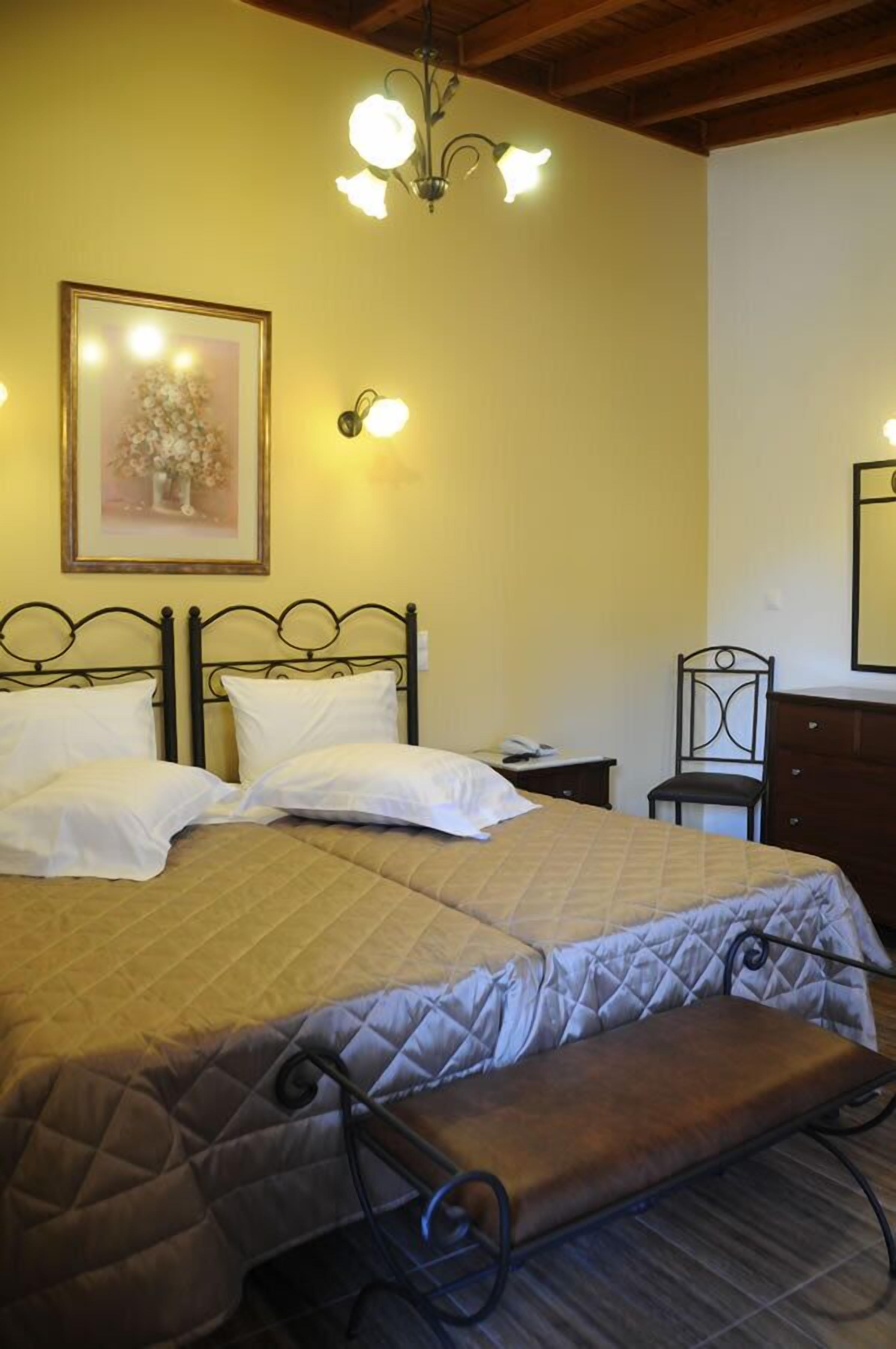A bedroom with a large bed, a bench, a nightstand, a chair, and a wall-mounted light fixture.