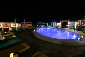 A pool area with lounge chairs and a small fountain.