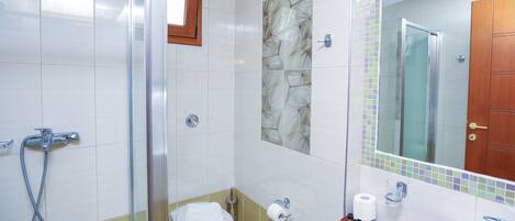 A bathroom with a glass shower enclosure, a toilet, and a sink with a mirror above it.
