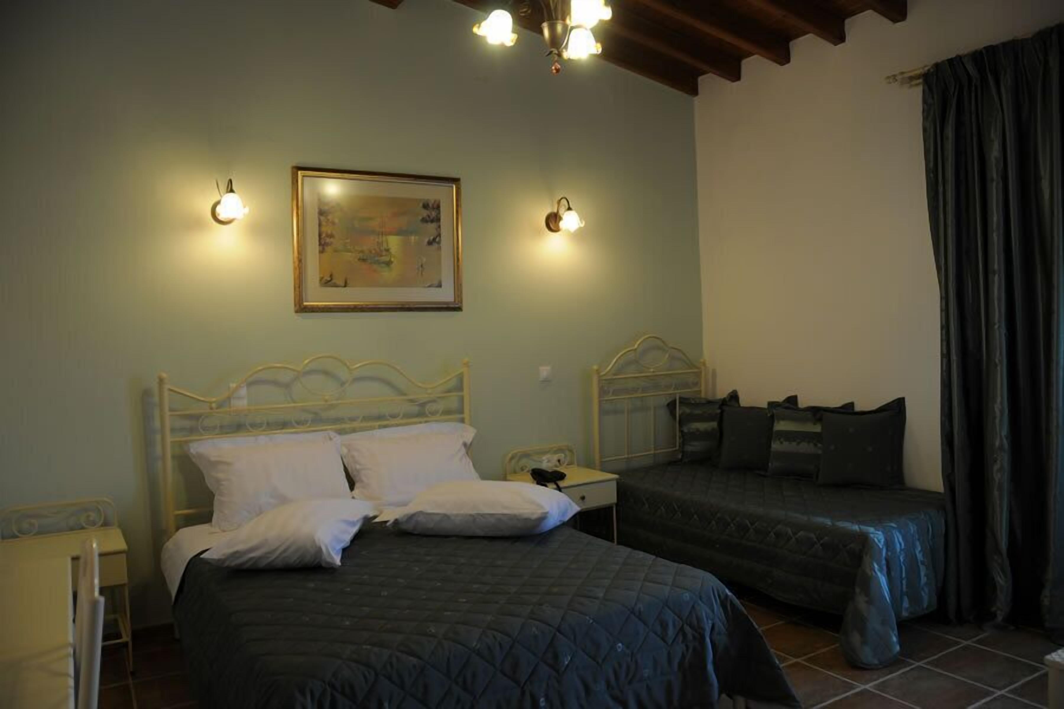 Quarto com duas camas, uma mesa de cabeceira, um abajur fixado na parede e um quadro.