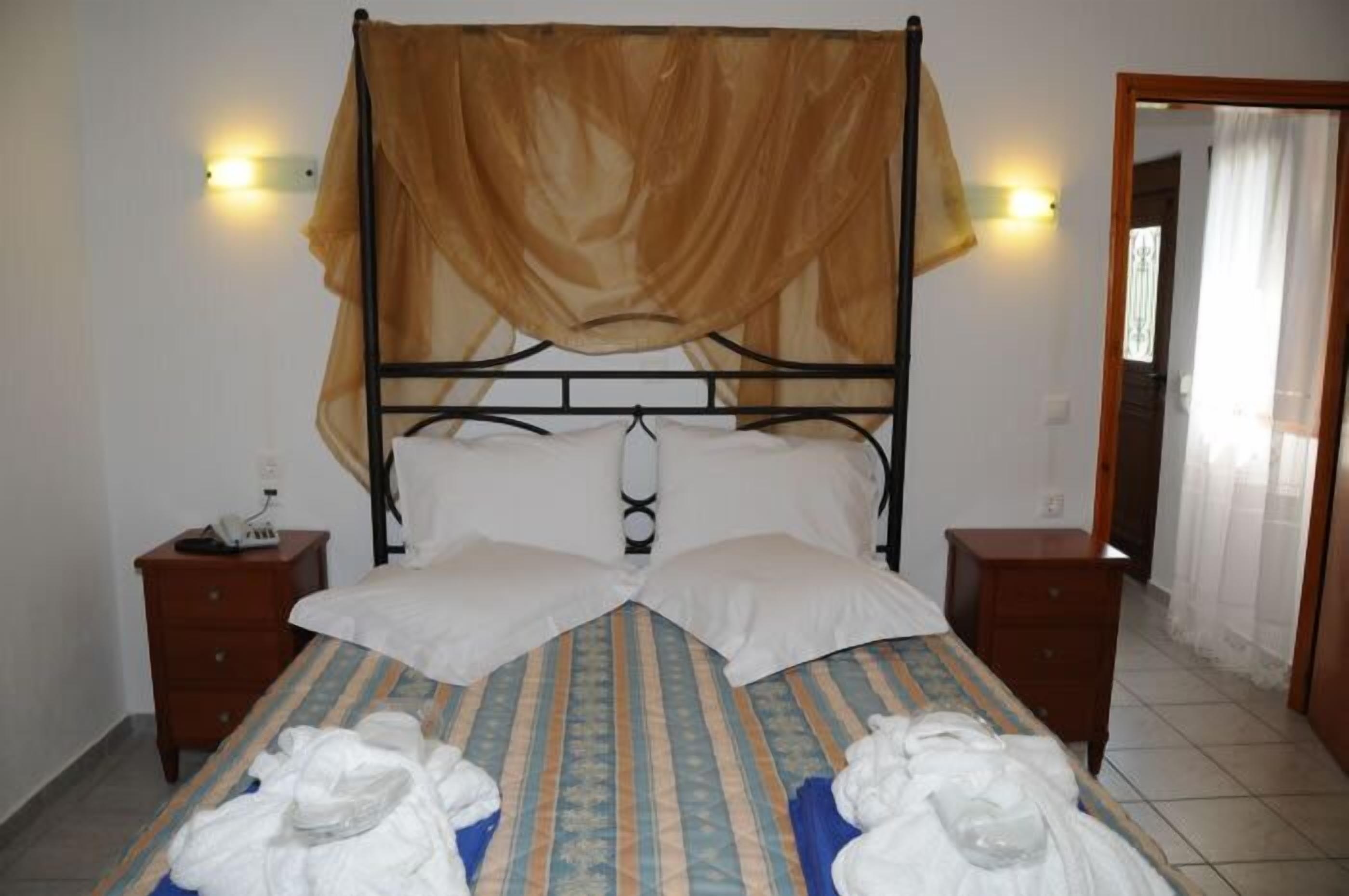 A bed with a canopy, two bedside tables, and a wall-mounted light fixture.