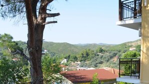 A stone pathway leading to a building with a red roof, surrounded by greenery and a view of hills. - Skiathos Island Suites (Skiathos)