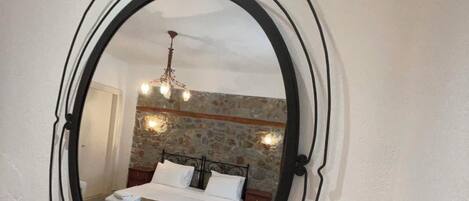 A bedroom with a bed, a mirror, and a vase on a table.
