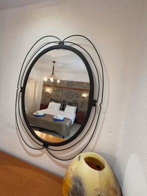 A bedroom with a bed, a mirror, and a vase on a table.