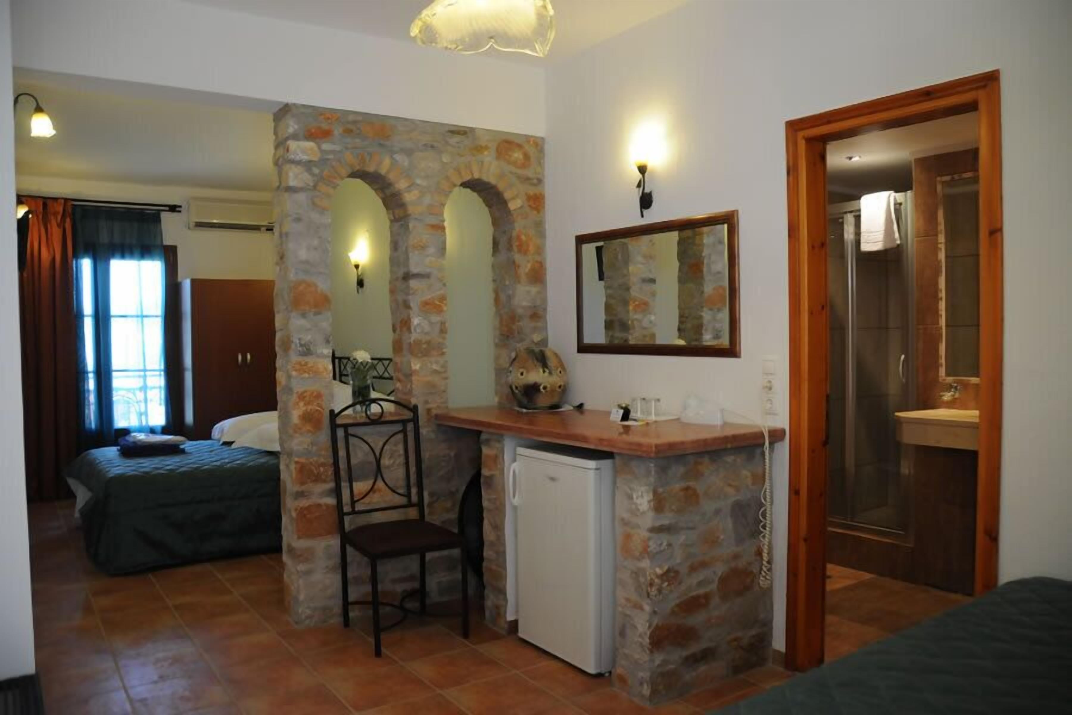 Een kleine kamer met een bed, een bureau met stoel, een spiegel en een douche.