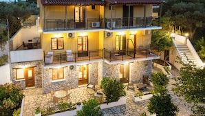 A multi-story building with balconies, outdoor seating, and stone walls. - Skiathos Island Suites (Skiathos)
