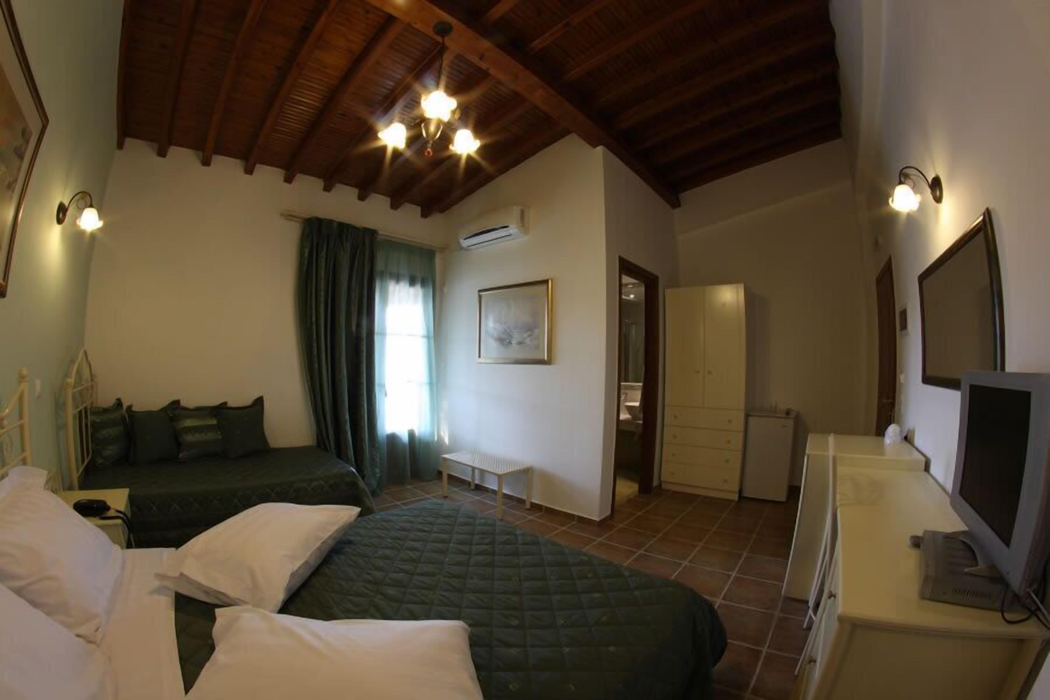 A room with two beds, a television, a desk, and a window with curtains.