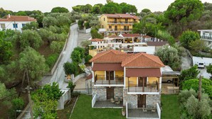 A multi-story residential building with a stone facade, multiple balconies, and a paved driveway. - Skiathos Island Suites (Skiathos)