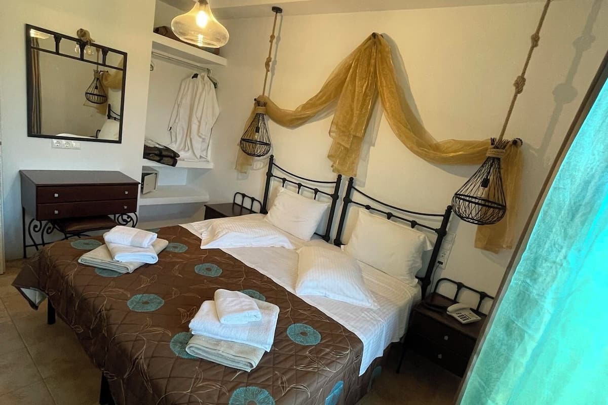Une chambre d’hôtel avec un grand lit, une table de chevet avec une lampe, un miroir et un luminaire suspendu.
