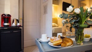 Una mesa de desayuno con cruasanes, una cafetera y un jarrón con flores.