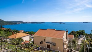 A coastal building with a tiled roof overlooking a clear blue sea. - Apartments Klis (Zupa dubrovacka)