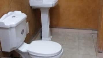 A small bathroom with a toilet, sink, and a trash bin.