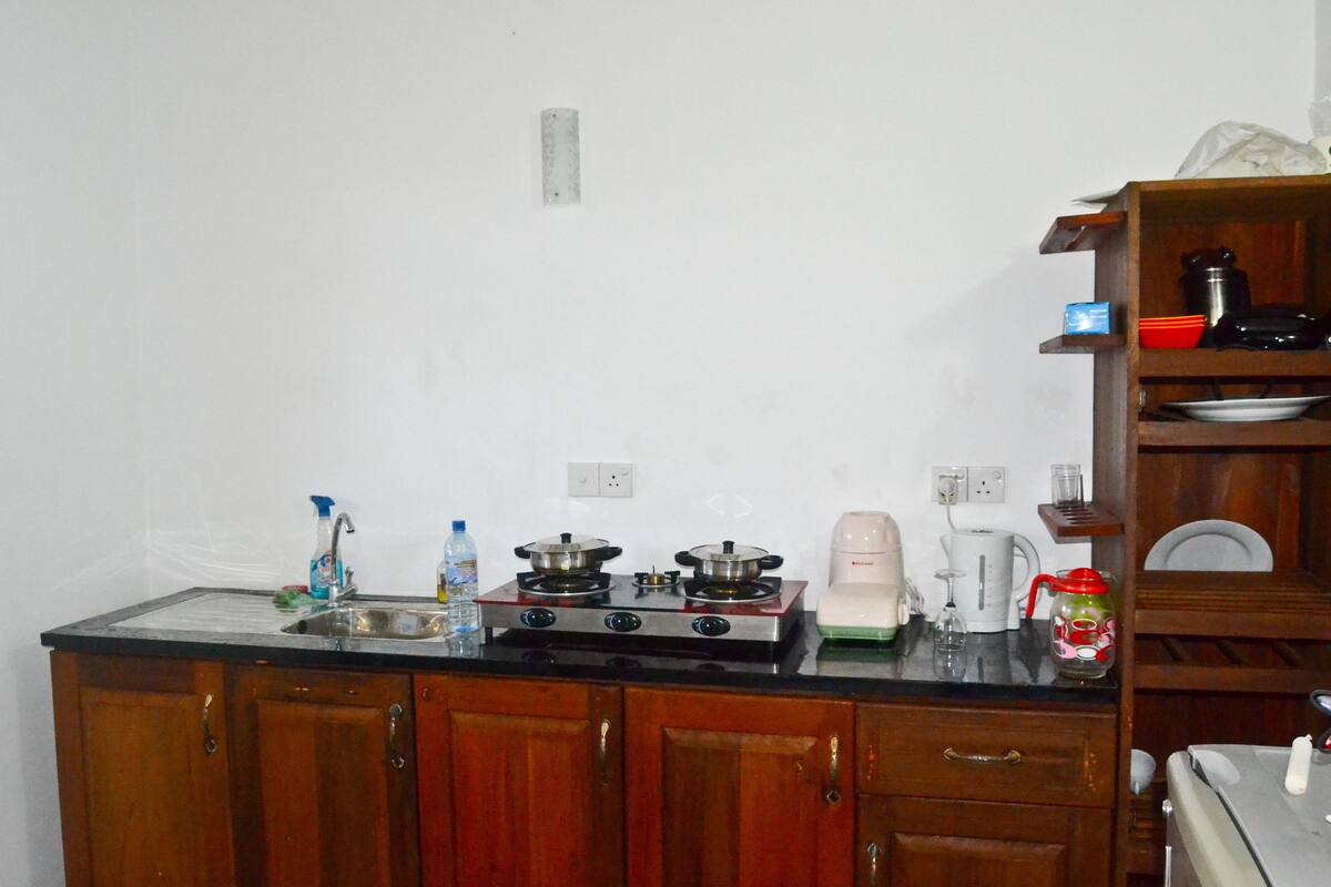 Cozinha com armários de madeira, fogão, pia e diversos eletrodomésticos.