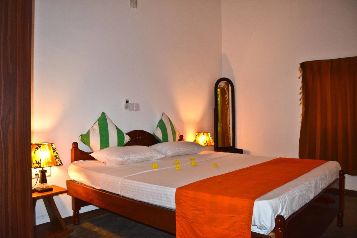 Uma cama bem arrumada com estrutura de madeira, duas luminárias de apoio e um espelho na parede.
