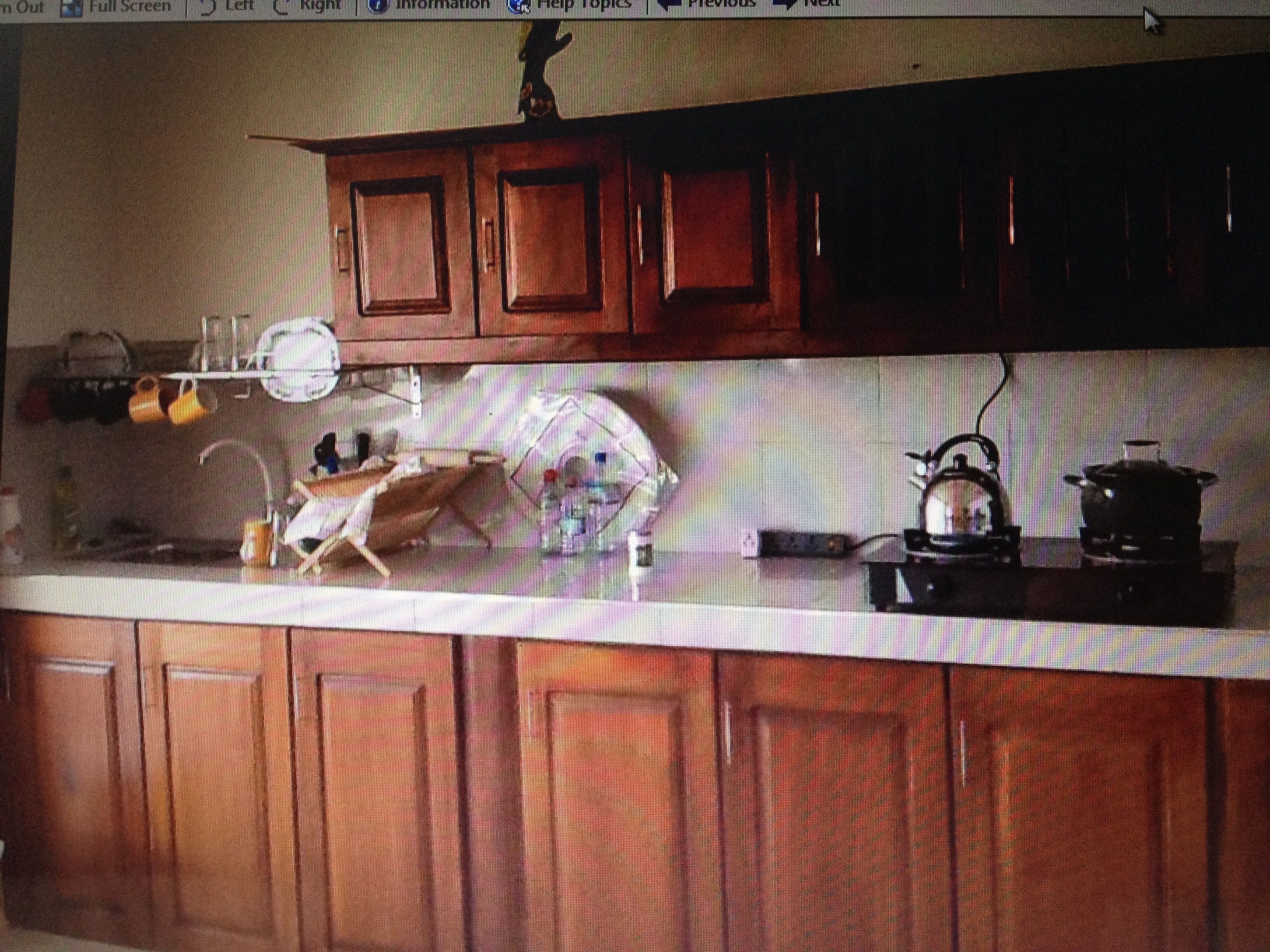 A kitchen with wooden cabinets, a countertop, and various kitchen items including a kettle and a pot.