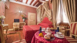 Une chambre avec un lit, une table avec des éléments pour le petit-déjeuner, une télévision et une fenêtre avec des rideaux.
