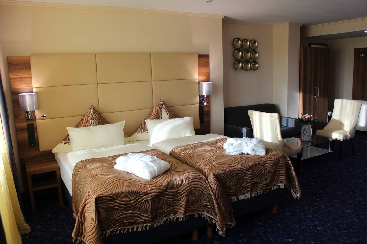 Quarto de hotel com uma cama grande, duas mesas de cabeceira, uma escrivaninha, uma cadeira e um espelho.