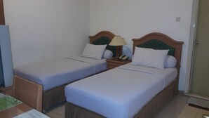 A hotel room with two single beds, a nightstand with a lamp, and a telephone. - Hotel Panakkukang (Makassar)