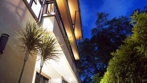 A modern building with a balcony, a palm tree, and dense foliage in the background. - Pensiri House (Sa Khu)
