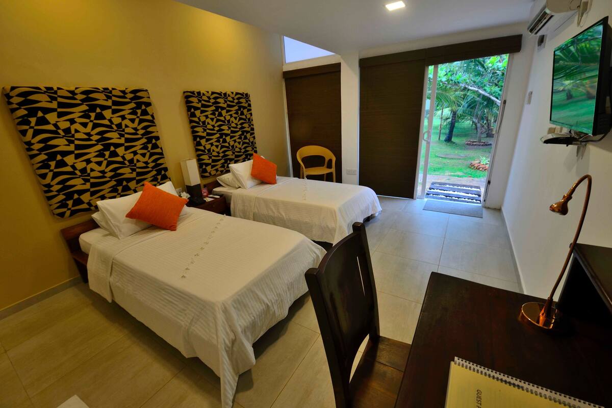 Habitación de hotel con dos camas, un escritorio, una silla y un televisor.