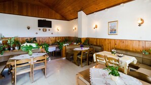 A restaurant with wooden tables and benches, potted plants, and wall-mounted lights. - Guesthouse Moretić (Dubrovnik)