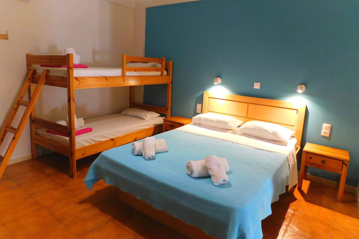 Een kamer met een stapelbed, een enkel bed en een nachtkastje.