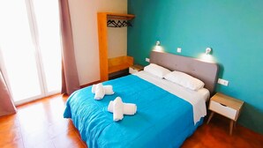 Une chambre à coucher comprenant un lit, une table de chevet, une étagère fixée au mur et une fenêtre.