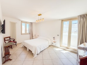 A bedroom with a bed, a chair, a desk, a lamp, and a window with curtains. - Palazzo Didonna - dimora storica (Rutigliano)
