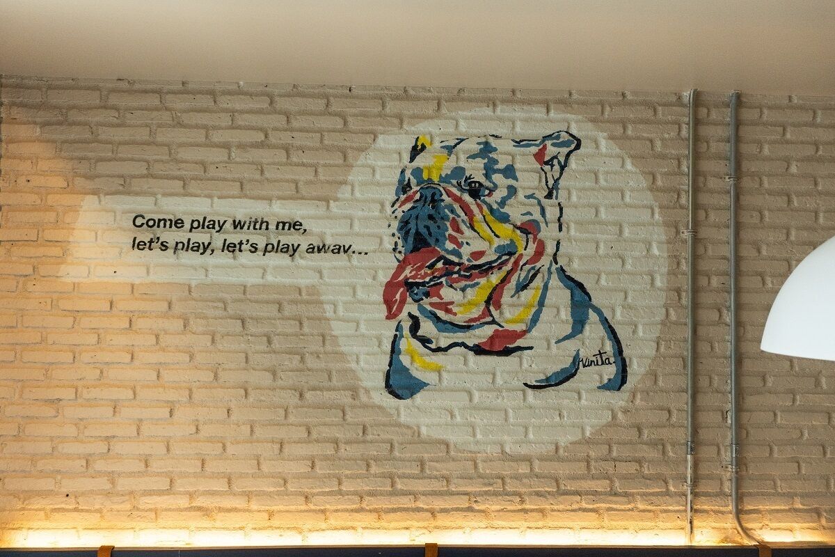 Pared con un mural de un perro e invitación a jugar.