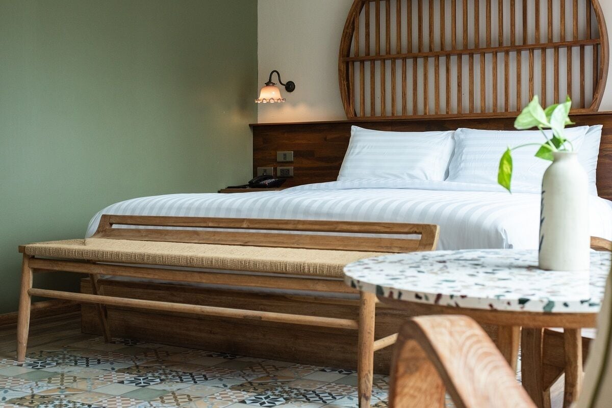 A bedroom with a bed, bedside table, lamp, and a small table with a vase.