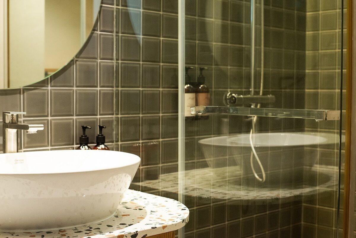 A bathroom with a round sink, a glass shower enclosure, and a tiled backsplash.